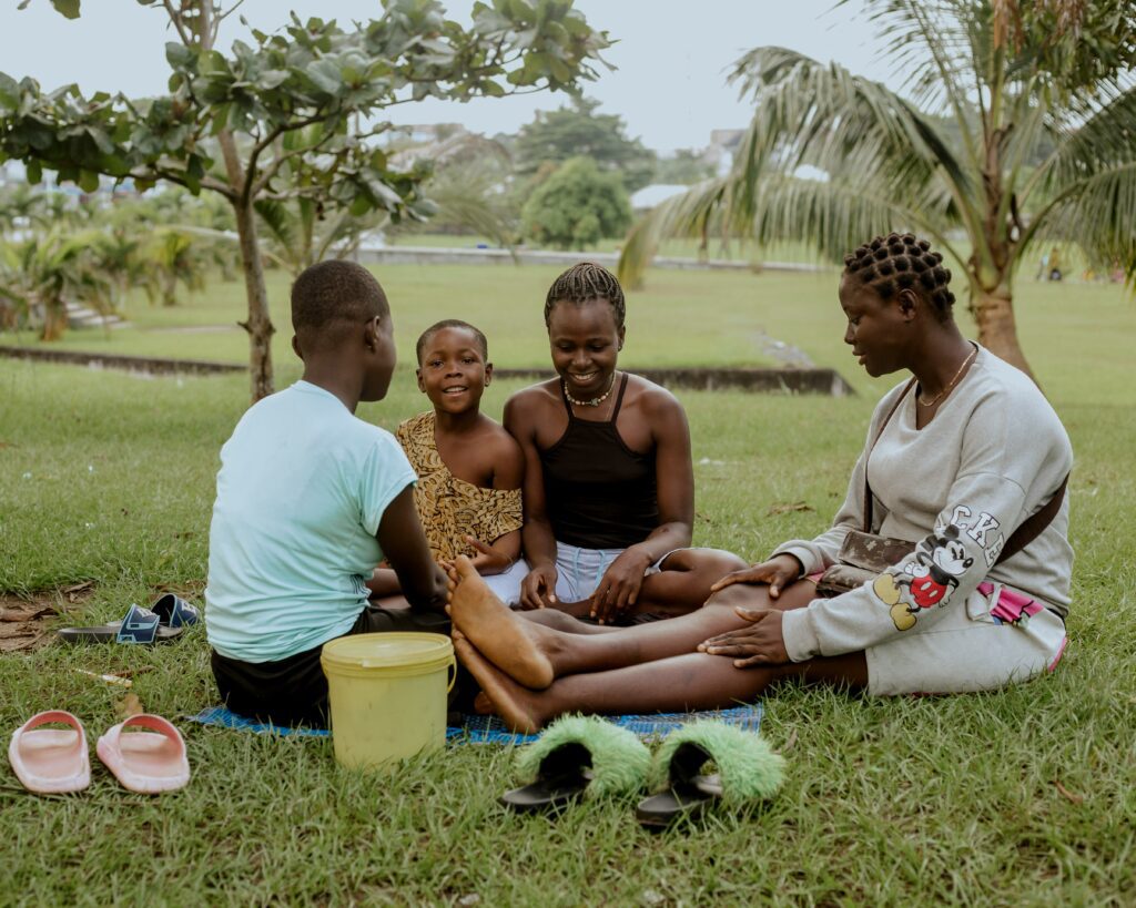 A family sits together on the grass in a park, reflecting the importance of long-term wealth protection and how revocable or irrevocable trusts can support family harmony across generations.