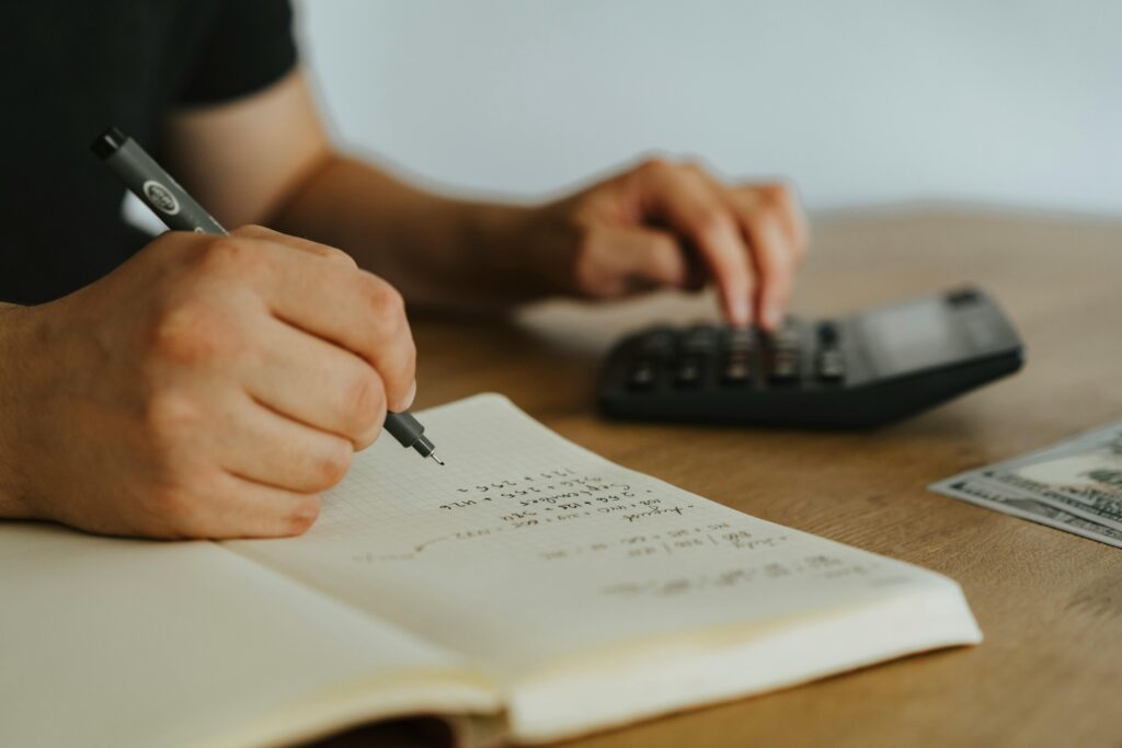 An image of a person writing in a booklet with a calculator.