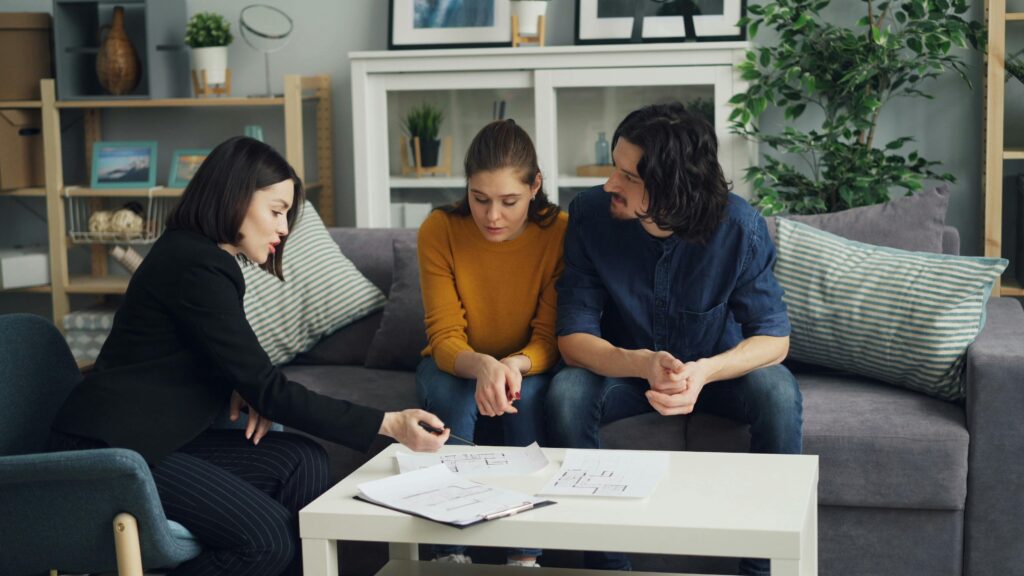 A couple meets with a real estate advisor in a modern home setting to discuss ownership structures and investment strategies.