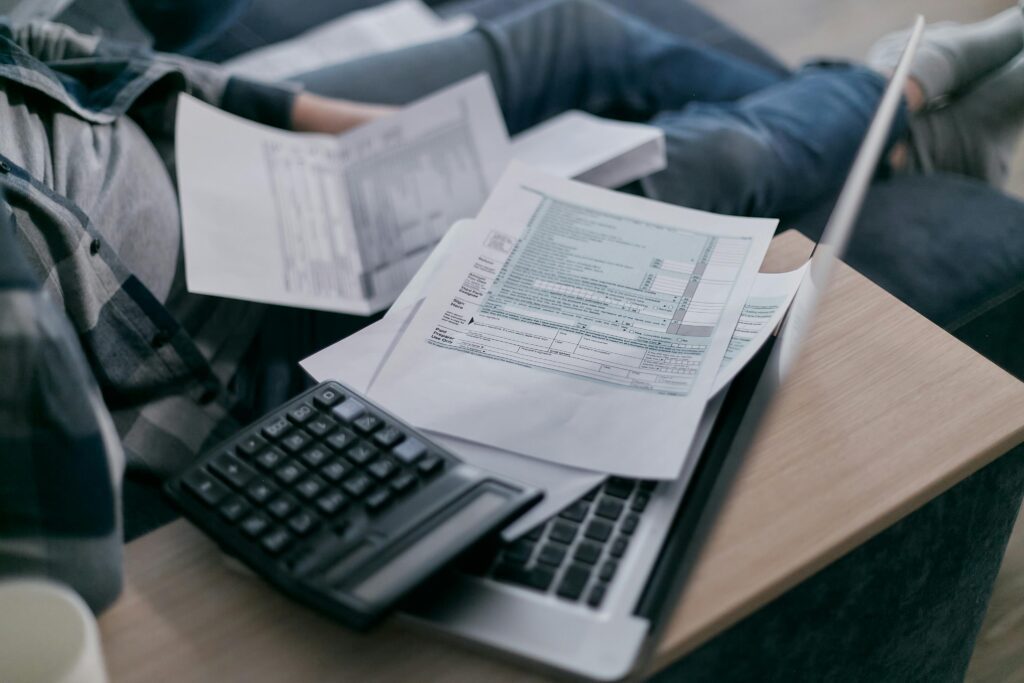 Flat lay of tax documents including W‑2 and W‑4 forms, with a calculator and pen—highlighting upcoming tax form complexity under 2026 payroll changes.