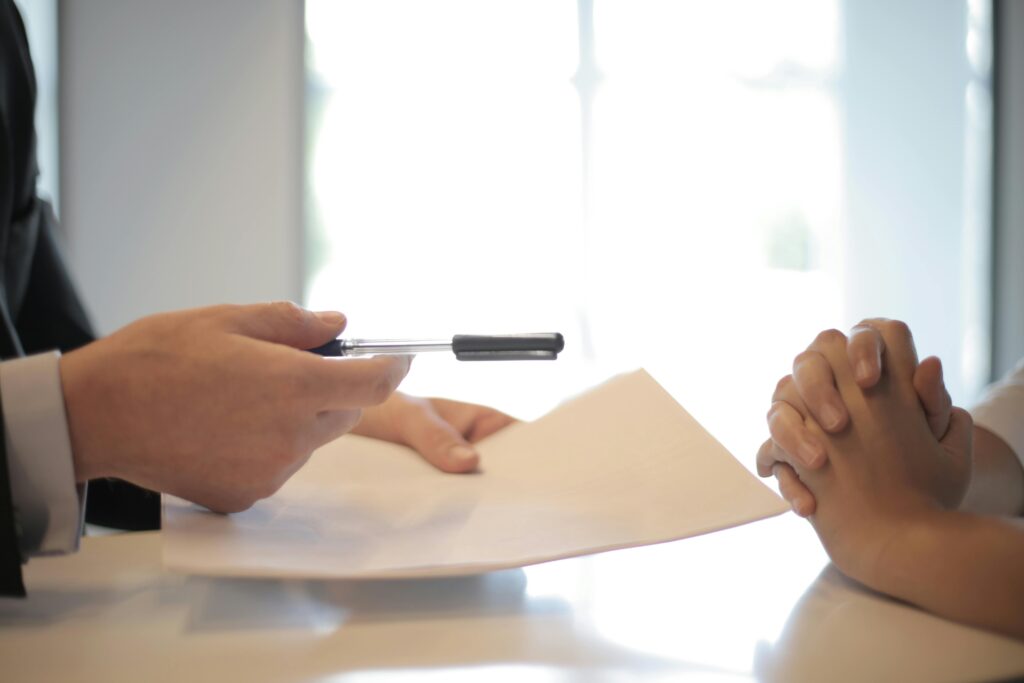 Image of a businessman giving a contract to a woman to sign.