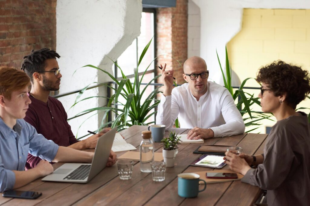 A business meeting with laptops, tablets, and coffee cups on the table, symbolizing the hybrid work environment and the pressure on accountants to stay adaptable and tech-savvy in 2025.
