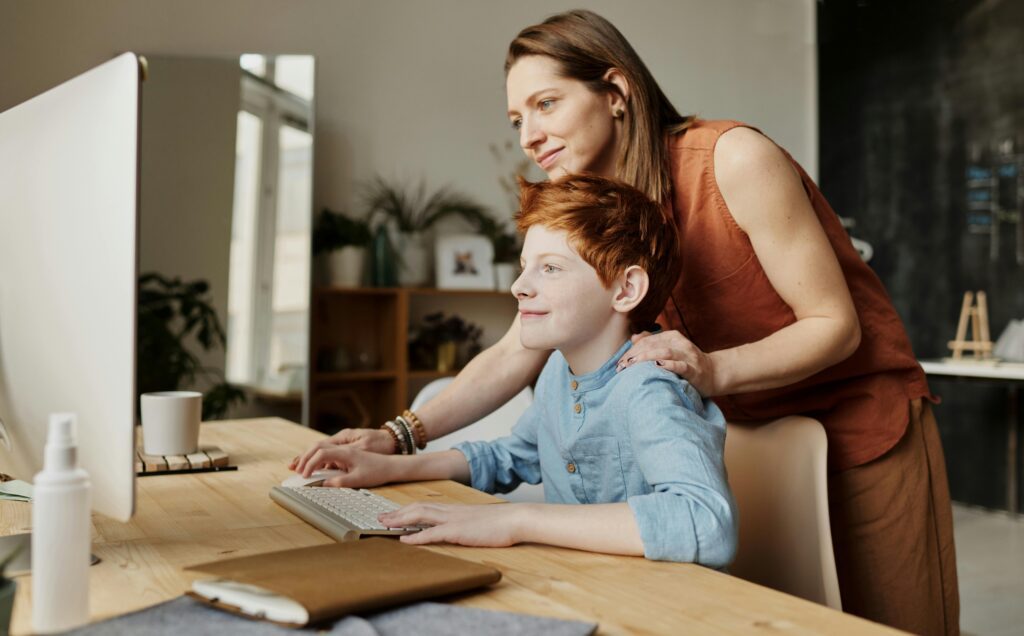 A woman is smiling while teaching her son, illustrating the concept of saving for education through 529 plans and Roth IRA rollovers.