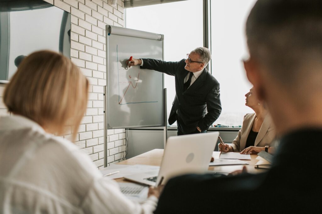 Financial advisor presenting an evergreen private equity fund strategy on a whiteboard during an investment meeting.