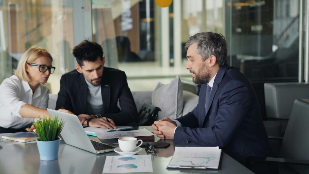 Business professionals discussing real estate investment strategy around a conference table.