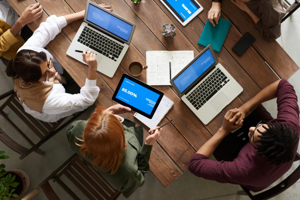Group of people collaborating on laptops and discussing technology implementation strategies.