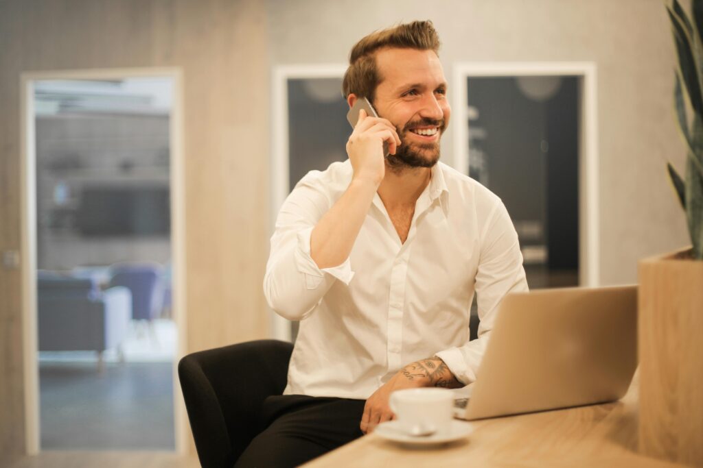Smiling professional male with a laptop engaging in a phone conversation for tax advice.