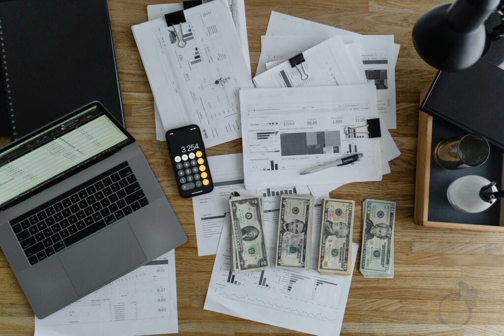Image of a laptop next to cash and paperwork to symbolize payroll stress for small businesses.