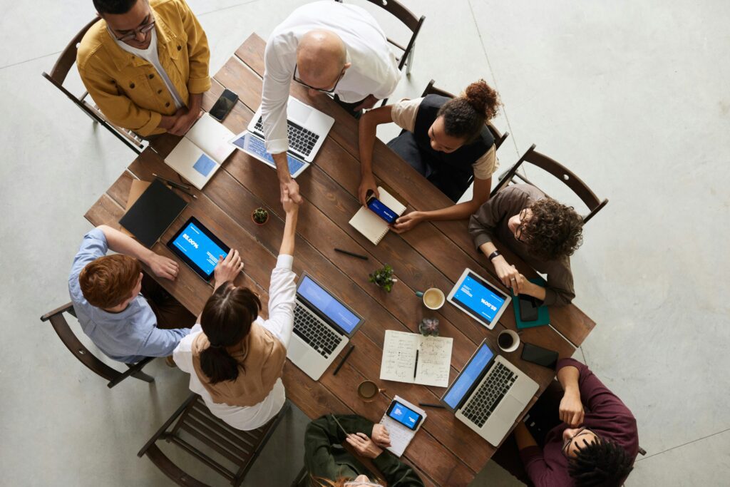 People shaking hands around a table, illustrating partnership and collaboration in the context of evolving tax technology strategies.