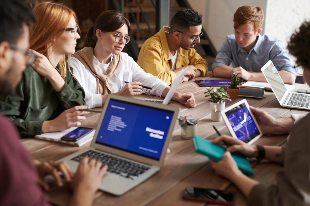 A group of people collaborating at a wooden table, symbolizing teamwork and strategic planning in a digital transformation context.